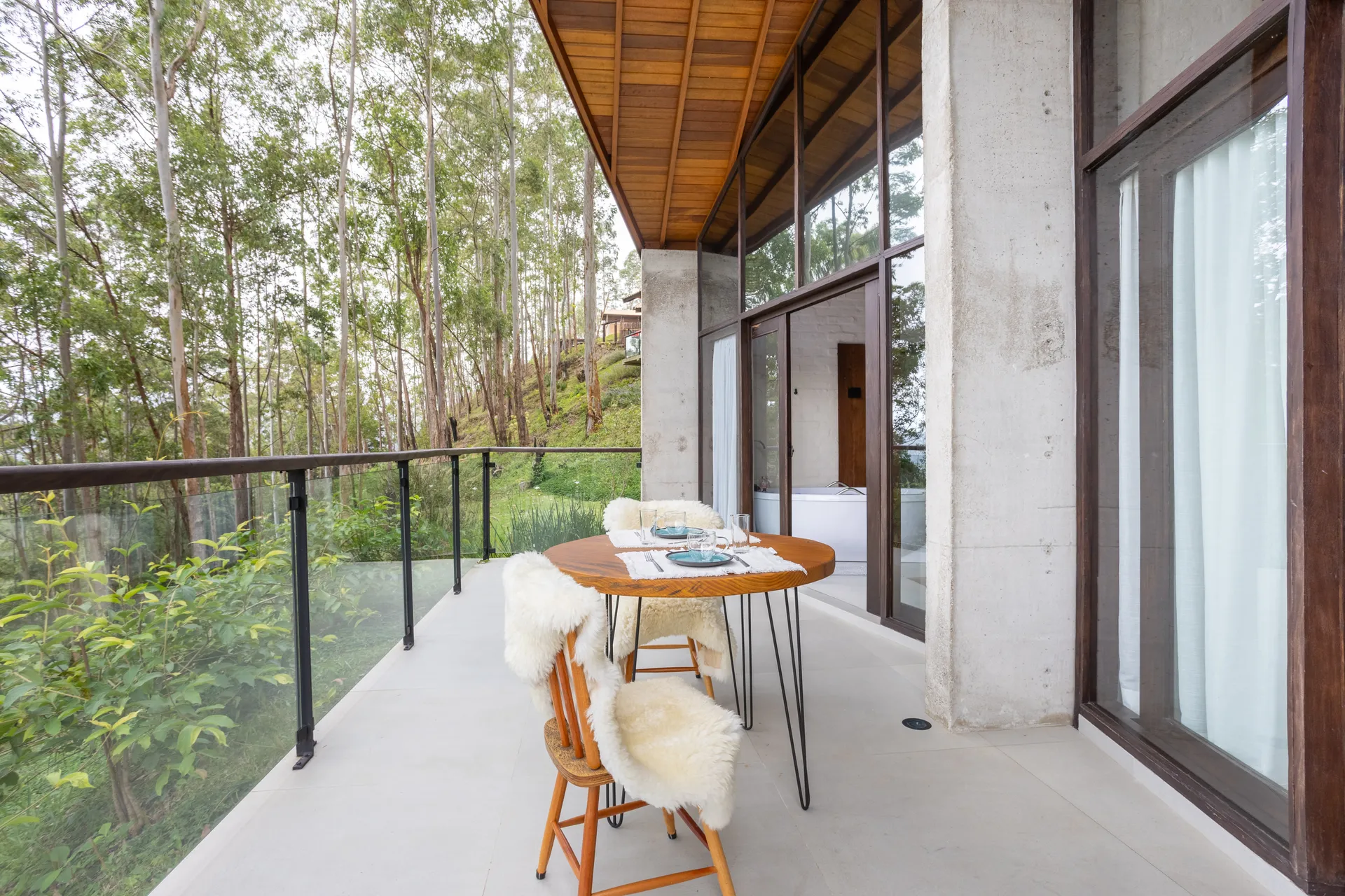 Varanda com mesa e cadeiras em meio às árvores